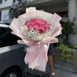 Pink rose bouquet wrapped in pale pink paper with white filler flowers