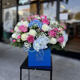 Bouquet of pink and white roses with blue hydrangeas in a blue box
