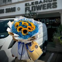 Bouquet of sunflowers and blue flowers wrapped in white paper