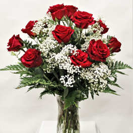 Red roses with white baby's breath in a clear glass vase