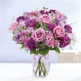 Pink and purple bouquet of roses and mixed blooms in a glass vase