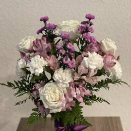 Pink and white bouquet in a glass vase with a purple ribbon