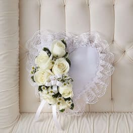 White rose bouquet with lace trim and ribbon on a cream tufted chair