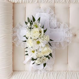 White floral cross with roses and daisies on a cushioned chair