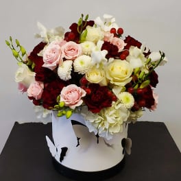 Mixed roses and white blooms in a white hatbox with butterfly cutouts