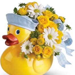 Yellow duck-shaped vase with yellow roses and white daisies