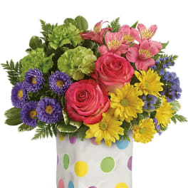 Colorful bouquet of roses, daisies, and alstroemeria in a polka-dot vase