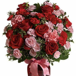Red roses and pink carnations in a red vase with a pink ribbon