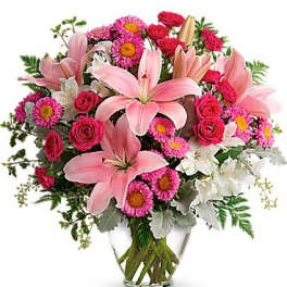 Pink lilies and mixed pink flowers in a clear glass vase