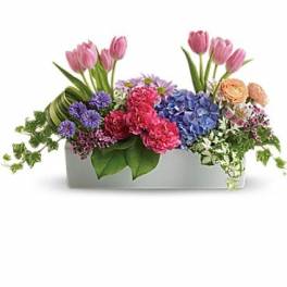 Mixed bouquet in a white rectangular container with pink tulips and blue hydrangeas