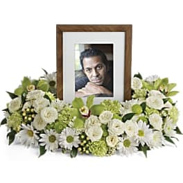 White floral arrangement surrounding a framed photo