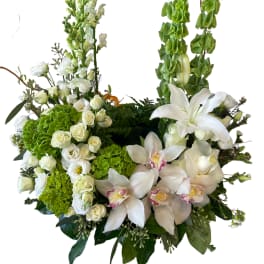 White floral arrangement with lilies, roses, and orchids