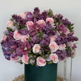 Pink roses and purple orchids in a green hatbox