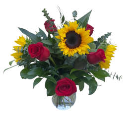 Red roses and sunflowers arranged in a clear glass vase