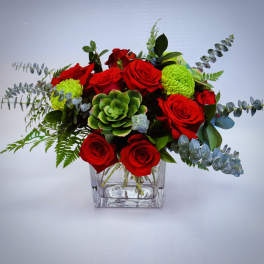 Low arrangement of red roses, green succulents, and green mums in a square glass vase