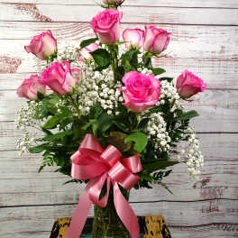 Pink roses in a glass vase with a pink ribbon bow