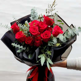 Bouquet of red roses wrapped in black paper with a red ribbon