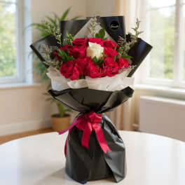Bouquet of red and white roses wrapped in black paper with a pink ribbon