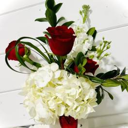 Red roses and white hydrangeas in a white vase with a red heart