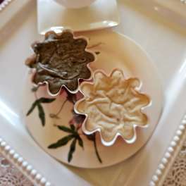 Two flower-shaped cups on a decorative tray with a square saucer.