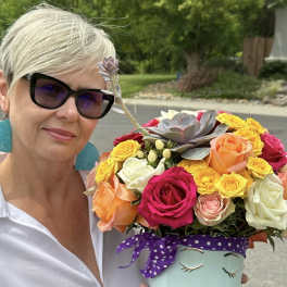 Woman holding a colorful bouquet in a painted face vase