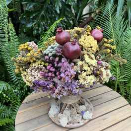 Dried flower arrangement with pomegranates in a low round container