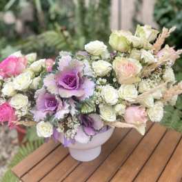 Pink and white roses with purple ornamental cabbage in a white vase