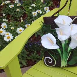White calla lilies arranged on a brown tote bag sitting on a lime-green chair.