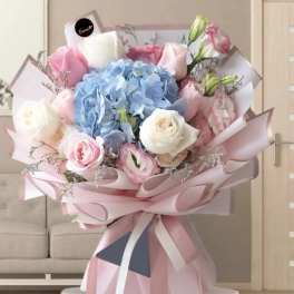 Pastel bouquet with blue hydrangea, pink and white roses, and ribbon wrap