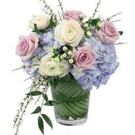 Bouquet of pink and white roses with blue hydrangeas in a glass vase