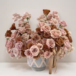Arrangement of pale pink and brown roses in a decorative vase