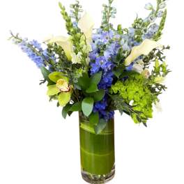 Blue and white floral arrangement in a tall glass vase