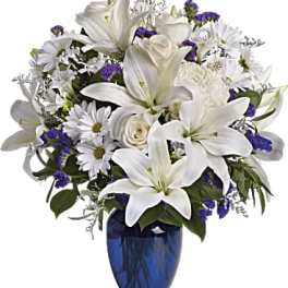 White lilies and daisies in a blue glass vase