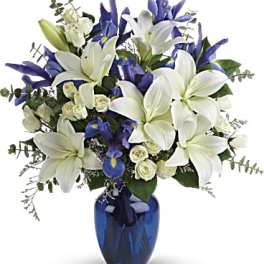 White lilies and blue iris in a blue glass vase