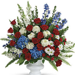 Red roses, white flowers, and blue blooms in a white vase