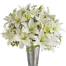 White lilies arranged in a tall silver vase