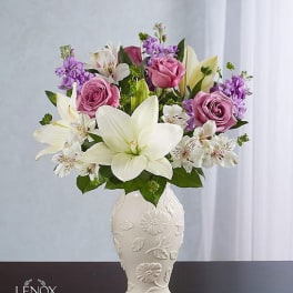 Pink roses and white lilies arranged in a decorative white vase