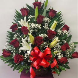 Basket arrangement of red roses and white lilies with a red bow
