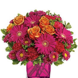 Bouquet of orange roses and magenta daisies in a pink glass vase