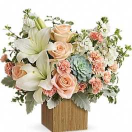 Peach roses and white lilies arranged in a wooden box with succulents