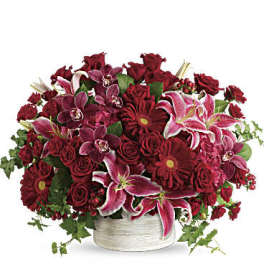 Red and pink mixed flower arrangement in a white basket