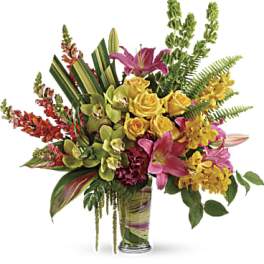 Mixed bouquet of roses, lilies, and orchids in a glass vase