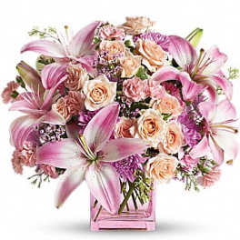 Pink lilies and peach roses arranged in a pink glass vase
