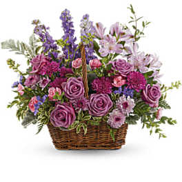 Basket arrangement of purple roses, lilies, and mixed blooms