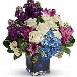 Bouquet of white roses, purple flowers, and blue hydrangea in a square vase