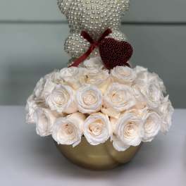 White rose arrangement with pearl teddy bears in a gold vase