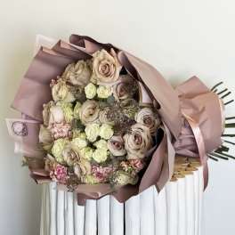 Bouquet of blush and cream roses wrapped in pink paper