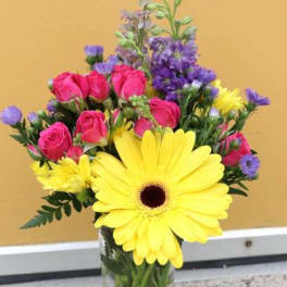 Bouquet of yellow gerbera daisies and pink roses in a glass vase
