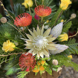Mixed bouquet with yellow roses and red pincushion protea in a vase
