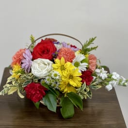 Basket arrangement of mixed roses, carnations, and daisies